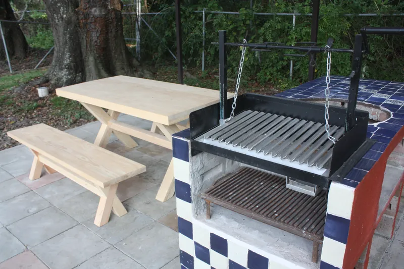 Asador de obra con parrilla estilo argentino y mesa de madera