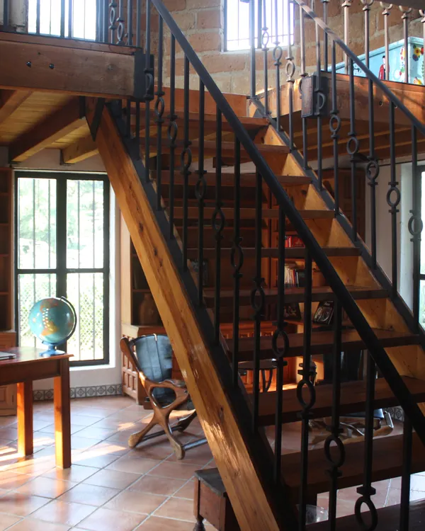Estudio con escritorio, libreros y una escalera de madera que sube al tapanco
