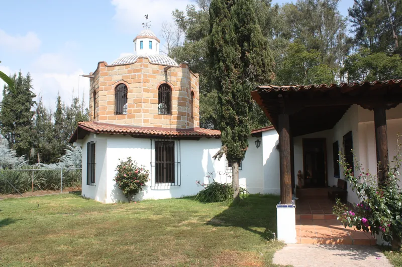 Entrada de la casa bajo un portal de madera, junto a la torre de ladrillo