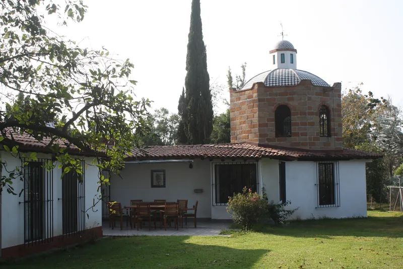 La casa y su torre con cúpula, con la terraza y el comedor exterior frente al jardín